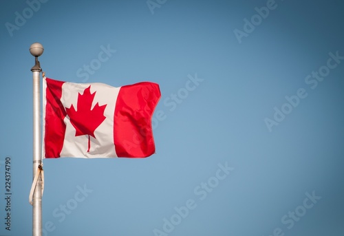 Canadian flag at in the wind with a blue sky at the back photo
