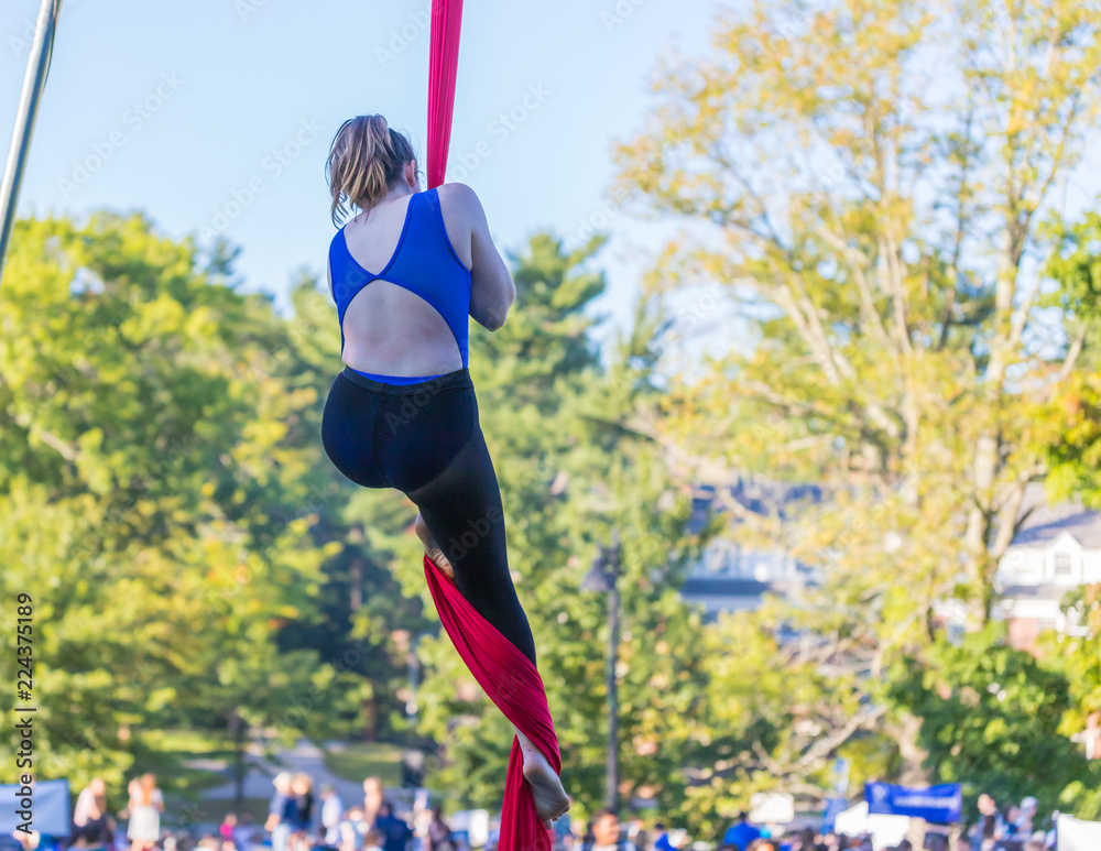Woman in blue dance outfit climbing a red ribbon