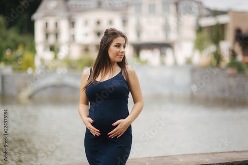 Young beautiful pregnant woman standing near the lake