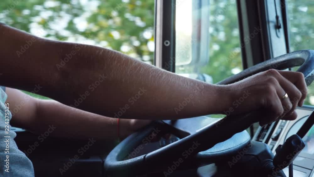 Unrecognizable man holding his hands on steering wheel and driving car at country road on warm summer day. Truck driver rides to destination. View from the lorry cab. Slow motion Close up