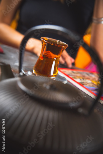 A cup of tea is in front of a girl in the foreground of a Chinese teapot. Чашка чаю стоит перед девушкой на переднем плане китайский чайник.