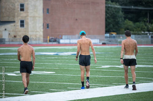 Three men runner are crossing a football stadium