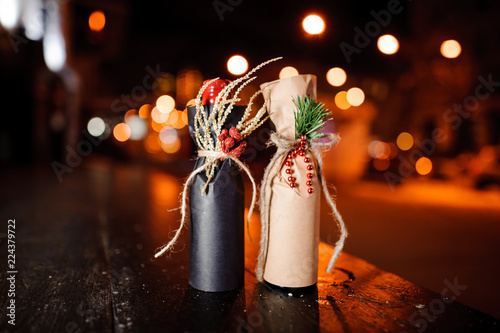 Two christmas decorated bottles standing on the wooden bench