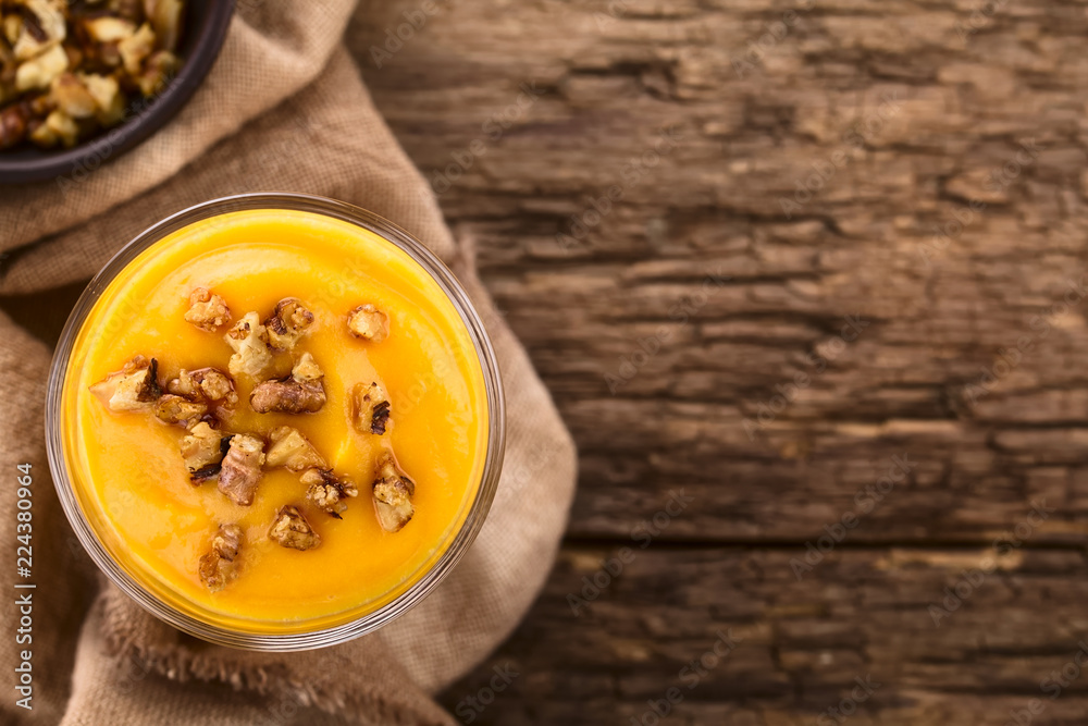 Hausgemachte Kürbismousse oder -pudding mit karamellisierten Walnüssen, fotografiert auf rustikalem Holz mit Textfreiraum an der Seite (Selektiver Fokus, Fokus auf das Dessert) Hausgemachte Kürbismousse oder -pudding mit karamellisierten Walnüssen, fotografiert auf rustikalem Holz mit Textfreiraum an der Seite (Selektiver Fokus, Fokus auf das Dessert)