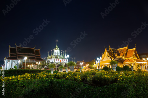 Landscape of the royal temple or Ratchanatda temple at night with yellow flowers at Bangkok, Thailand. It is popular with both Thai and foreign tourists. The beauty of Bangkok at night concept.