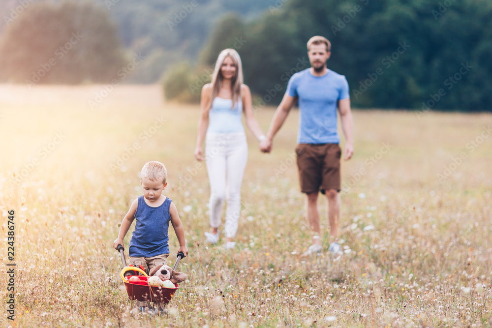 Fototapeta premium Child with his parents pushing a whellbarrow outdoors