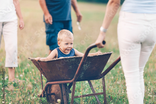 Family pushing their small child in a wheelbarrow