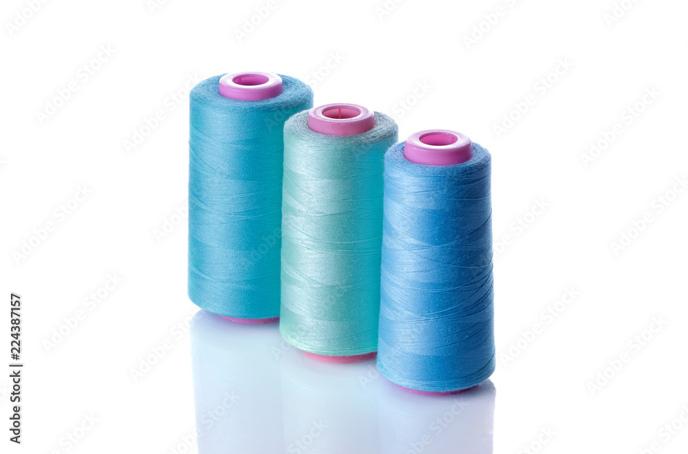 A bobbin with threads in blue tones on a white isolated background. accessories for sewing A bobbin with threads in blue tones on a white isolated background. accessories for sewing