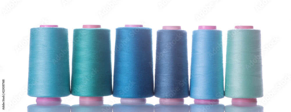 A bobbin with threads in blue tones on a white isolated background. accessories for sewing A bobbin with threads in blue tones on a white isolated background. accessories for sewing