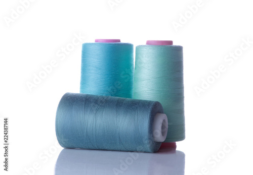 A bobbin with threads in blue tones on a white isolated background. accessories for sewing