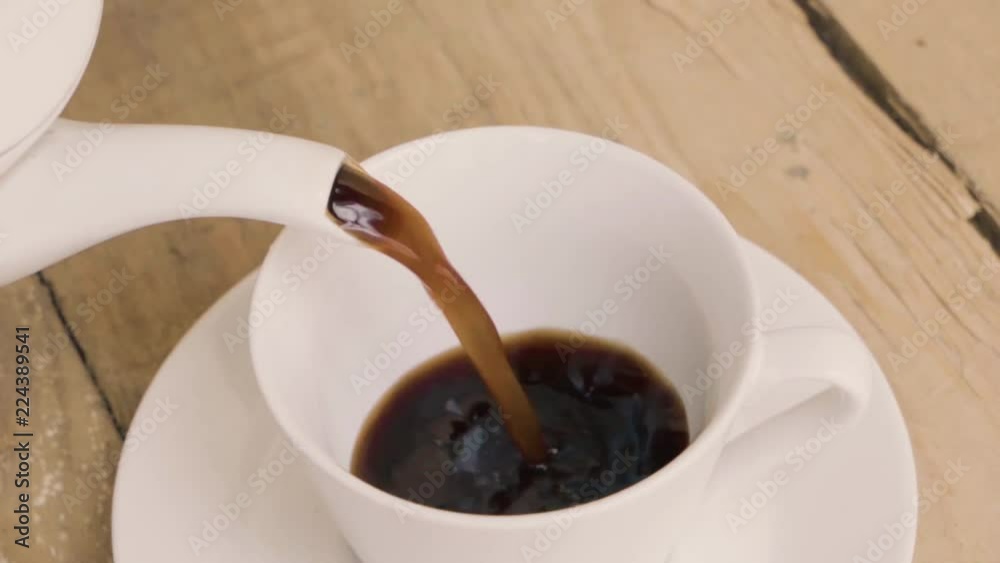 Top view of hot coffee pouring into a cup on the wooden background