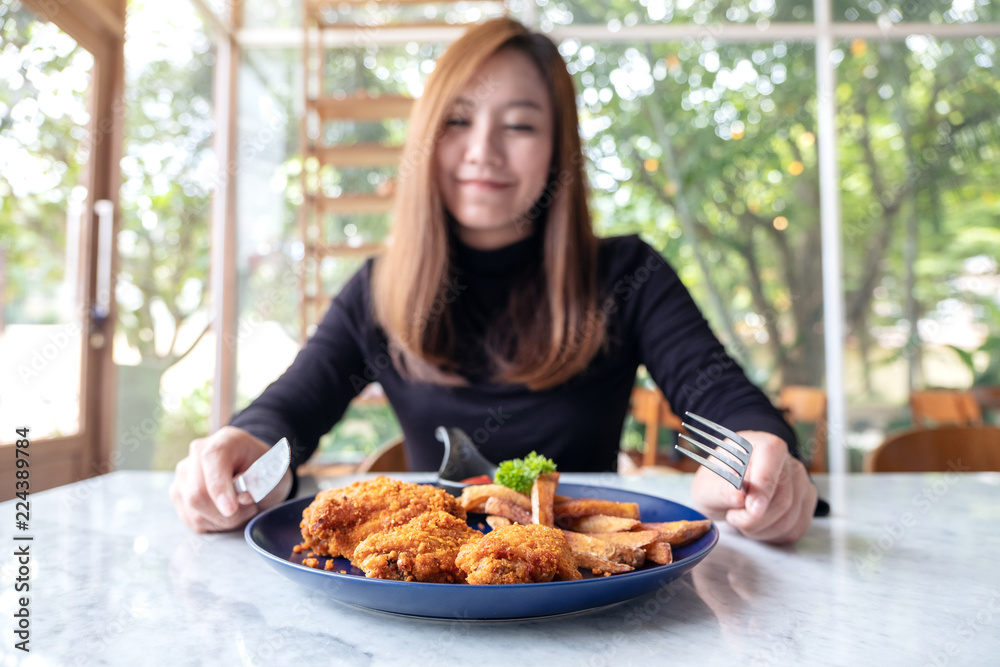 Closeup image of a beautiful asian woman enjoy eating fried chicken and french fries in restaurant Closeup image of a beautiful asian woman enjoy eating fried chicken and french fries in restaurant