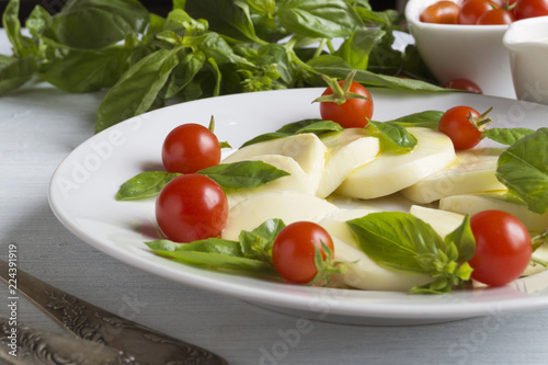 Caprese salad with ripe tomatoes and mozzarella with fresh Basil leaves. Italian food.