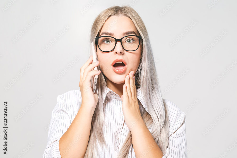 Wow! It's amazing news! Photo of surprised cheerful cute beautiful young woman chatting by mobile phone isolated over white background. Wow! It's amazing news! Photo of surprised cheerful cute beautiful young woman chatting by mobile phone isolated over white background.