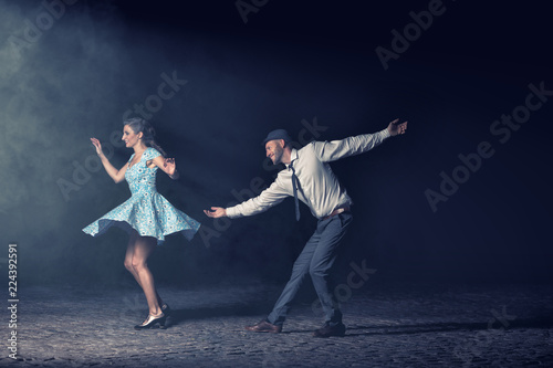 Couple dancing lindy hop at night in front of a spotlight. photo