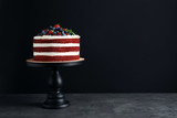 Stand with delicious homemade red velvet cake and space for text on black background