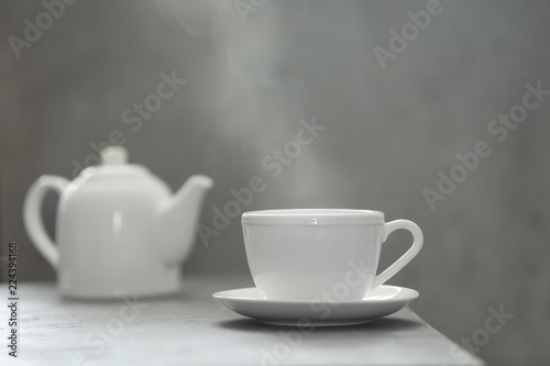 Cup of tea and saucer on table against gray background