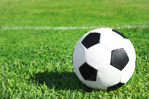 Soccer ball on fresh green football field grass. Space for text