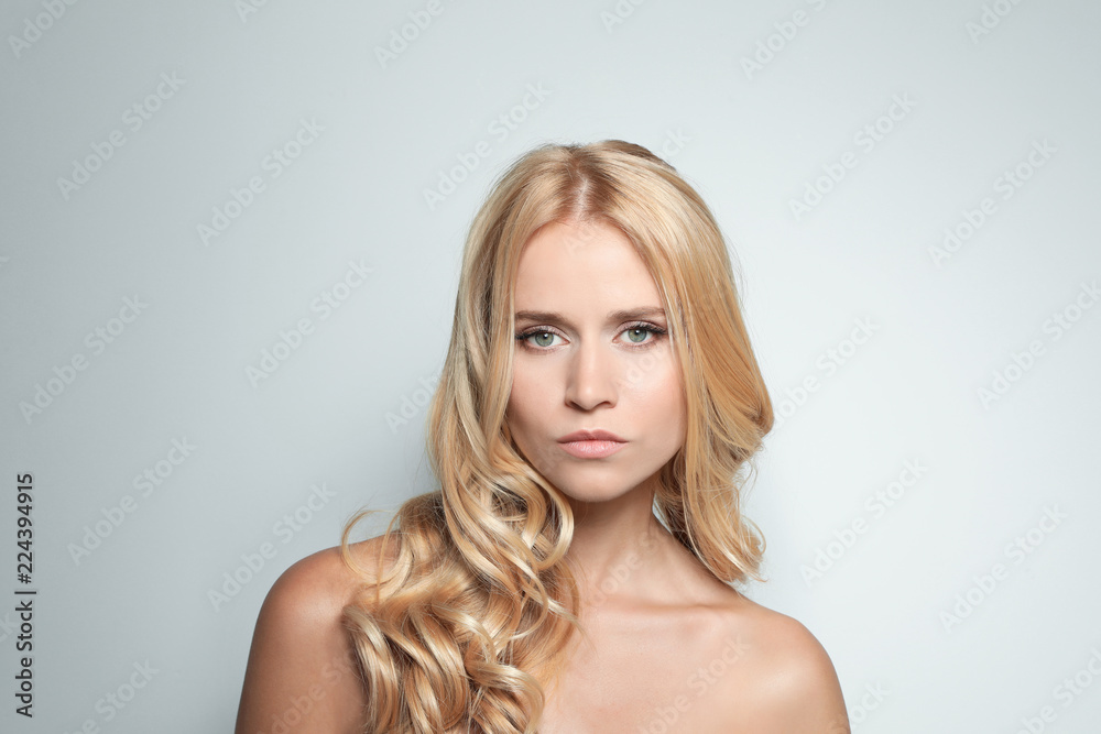 Beautiful woman with healthy long blonde hair on light background