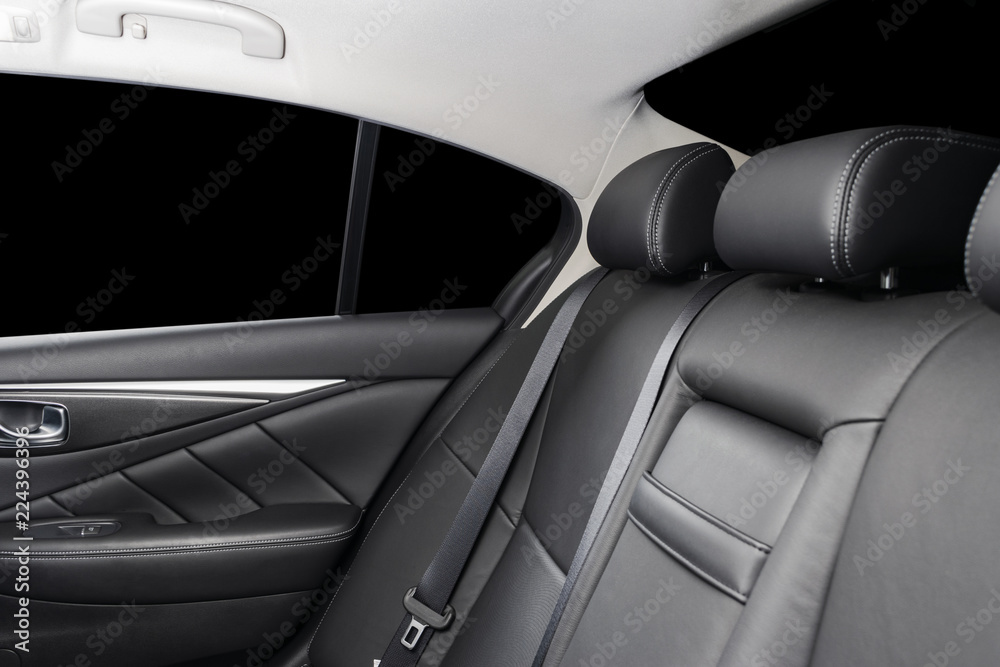 Back passenger seats in modern luxury car, frontal view. Black perforated leather with white stitching. Car detailing. Leather comfortable black seats. Car interior details