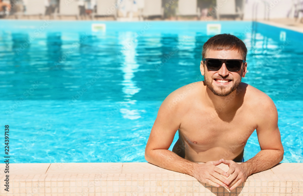 Young bearded man in swimming pool at resort. Space for text