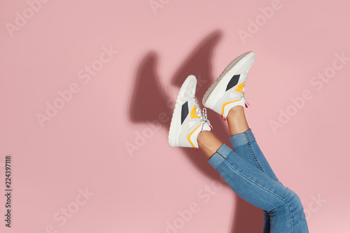 Kobieta w eleganckich sneakers blisko kolor ściany, zbliżenie. Miejsce na tekst