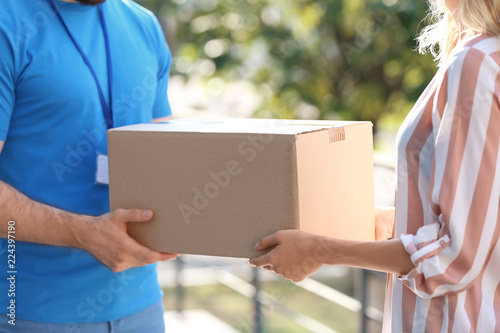 Woman receiving parcel from deliveryman on blurred background, closeup. Space for text © New Africa
