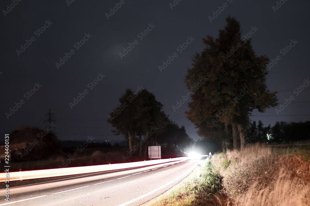 A road picture with a timelaps light line taken at a night.