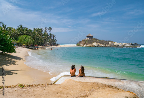 Back view of young couple sitting by the sea in Colombia, Tayrona
