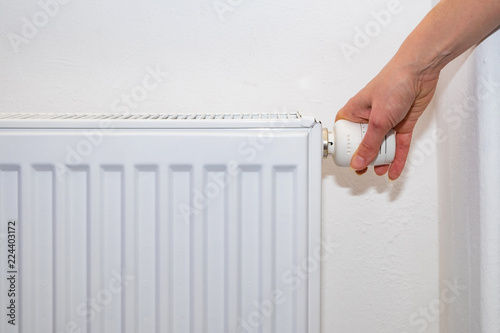 Wallpaper Mural Female hand regulates the thermostat knob on the white heating radiator with at home a cold season. Torontodigital.ca
