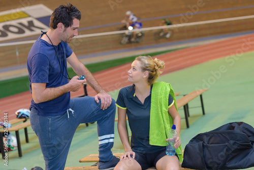 female racing cyclist on velodrome talking to coach