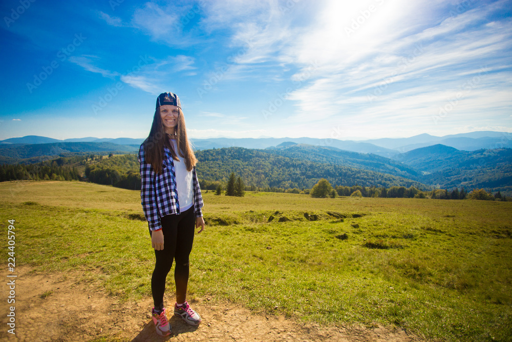 Young happy woman on top of hill enjoy beautiful view of sky and mountains, freedom and harmony concept