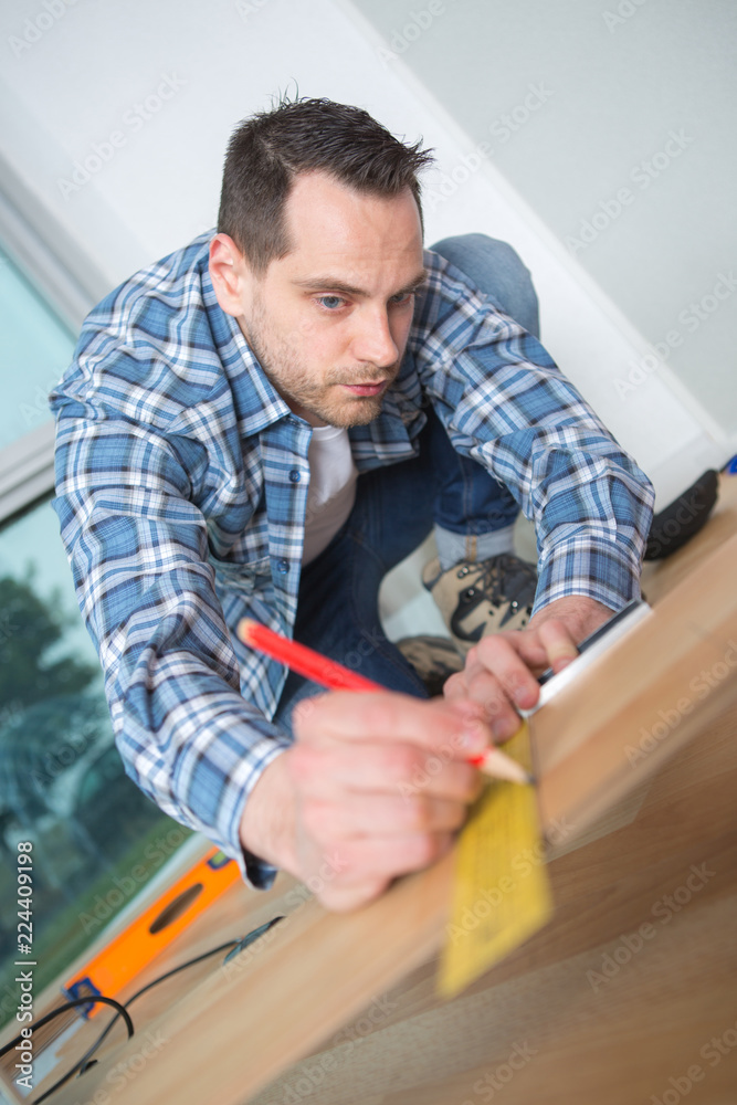 Man measuring floor board Man measuring floor board