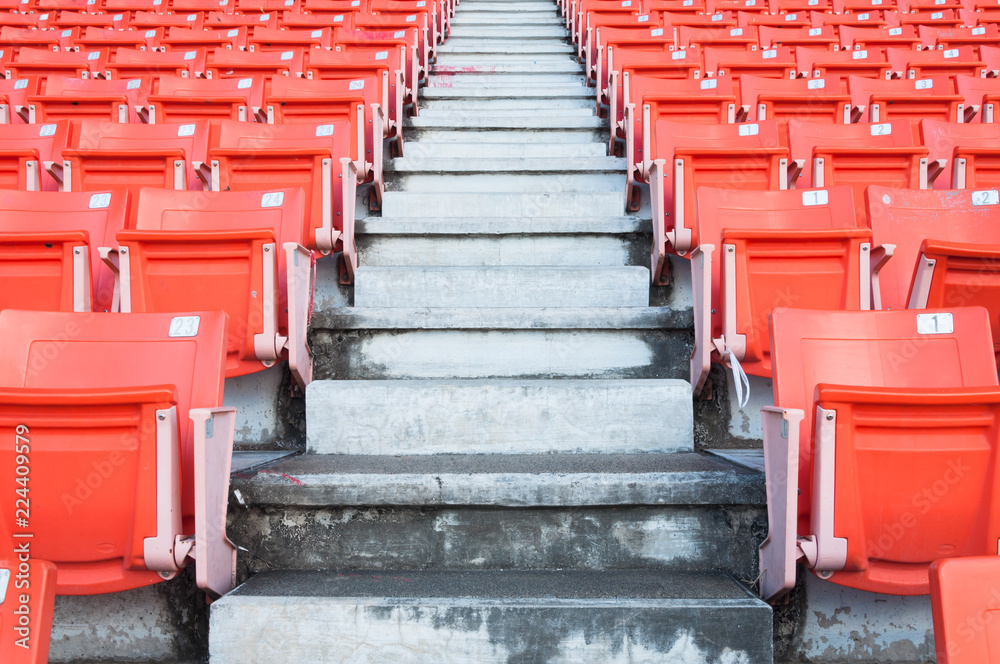 Empty orange seats at stadium,Rows walkway of seat on a soccer stadium Empty orange seats at stadium,Rows walkway of seat on a soccer stadium