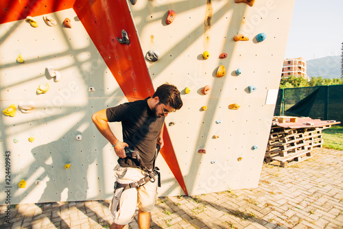 Sporty man prepare climbing on artificial rock wall