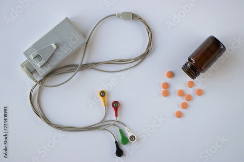 Device of holter monitoring and pills on white background. The concept of diagnosis and treatment of cardiovascular diseases.