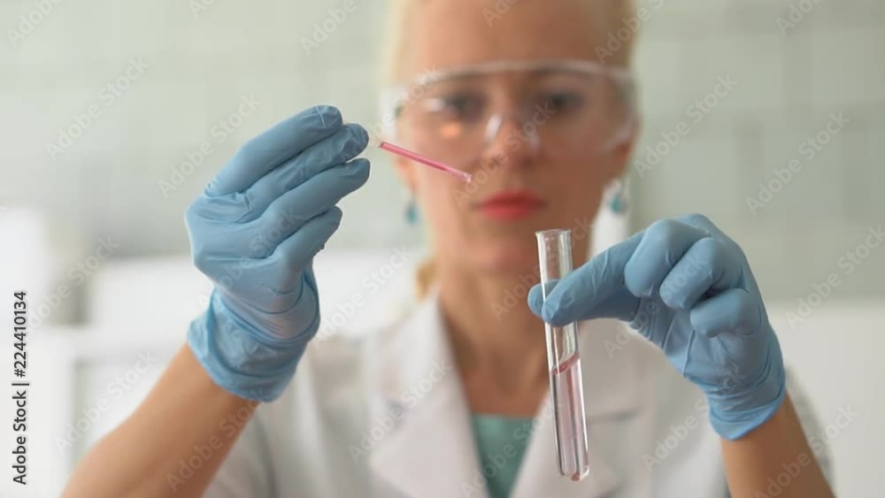 Scientist pouring red liquid in test tubes in a laboratory. HD Scientist pouring red liquid in test tubes in a laboratory. HD