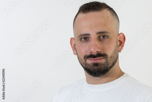 young businessman with tattoo, black t-shirt, beard and black hair, and with a white background