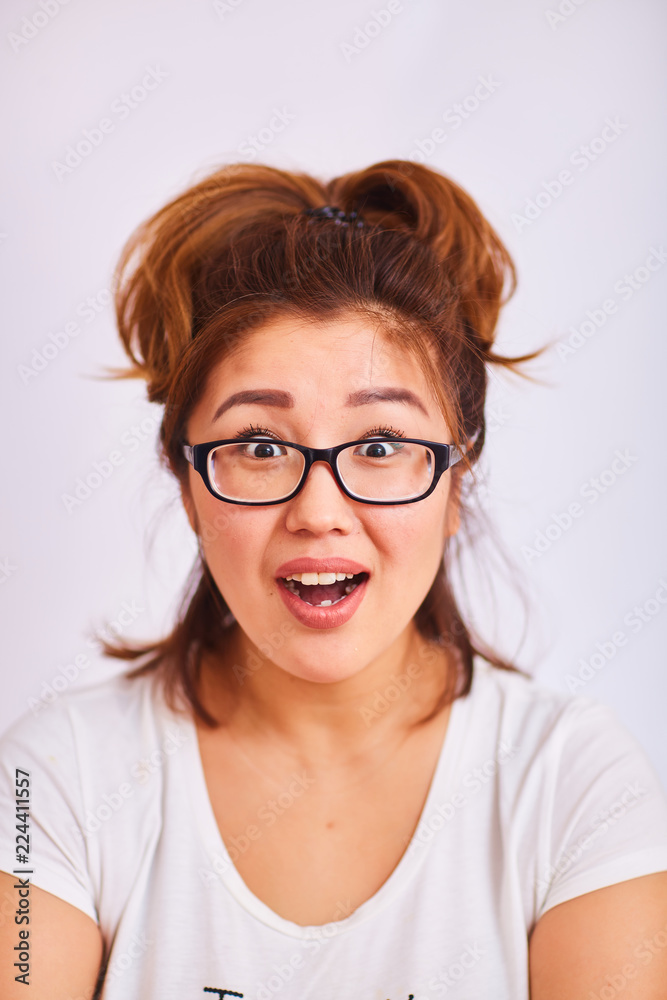 Obraz premium A girl in glasses smiles and looks with surprised eyes