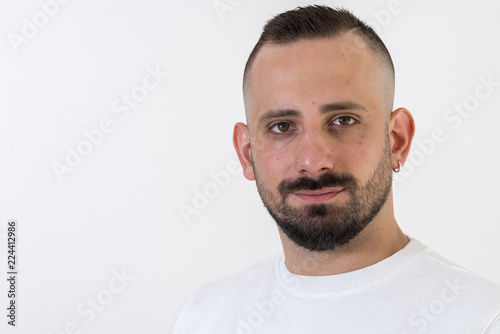 young businessman with tattoo, black t-shirt, beard and black hair, and with a white background