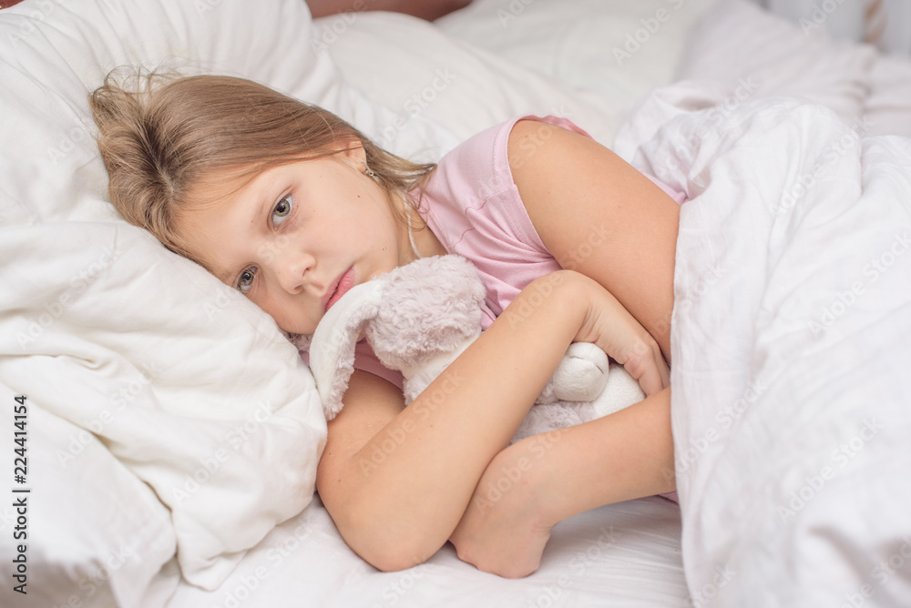 little girl lying in bed with abdominal pain, painful disease, feeling unwell, ache concept little girl lying in bed with abdominal pain, painful disease, feeling unwell, ache concept