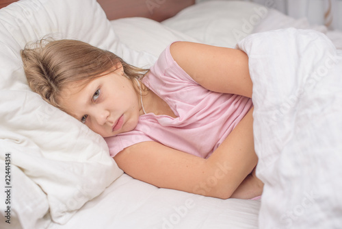 little girl lying in bed with abdominal pain, painful disease, feeling unwell, ache concept