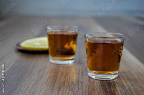 a two piles of whiskey and slices of lemon on a wooden background
