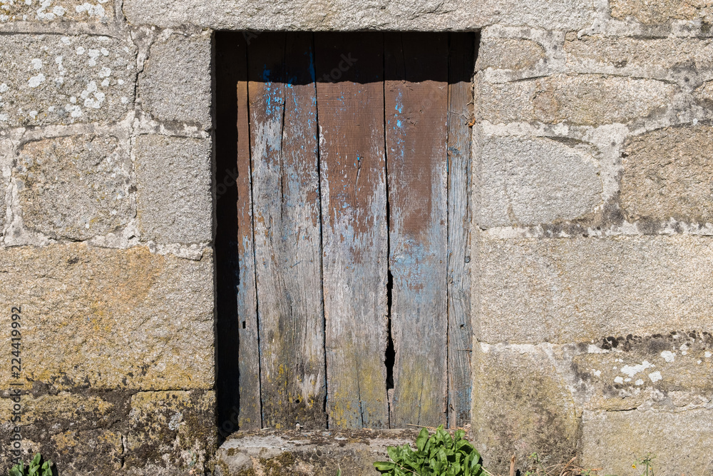 Puerta vieja de madera marrón en construcción de muro de piedra. A Limia, Ourense. Galicia, España. Puerta vieja de madera marrón en construcción de muro de piedra. A Limia, Ourense. Galicia, España.