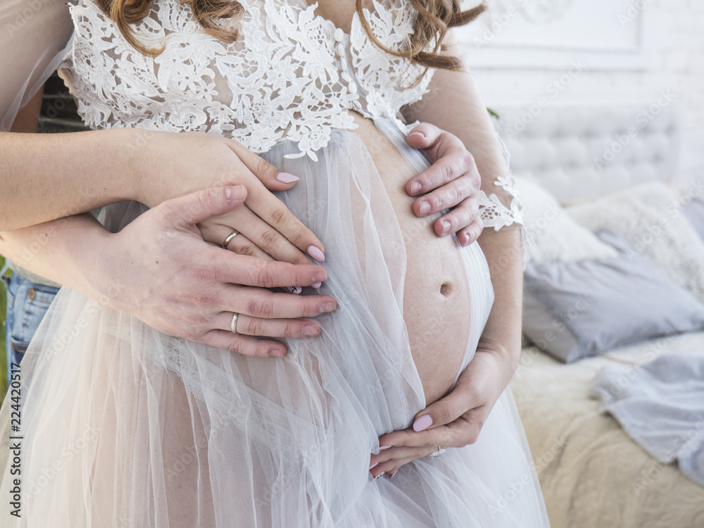 Future parents expecting baby. Close up of pregnant belly. Male and female hands hug the pregnant belly. Beautiful pregnant woman and her handsome husband hugging the tummy. Love concept.