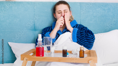 Εκτύπωση καμβά Portrait of sick woman with rhinitis lying in bed and using nasal spray