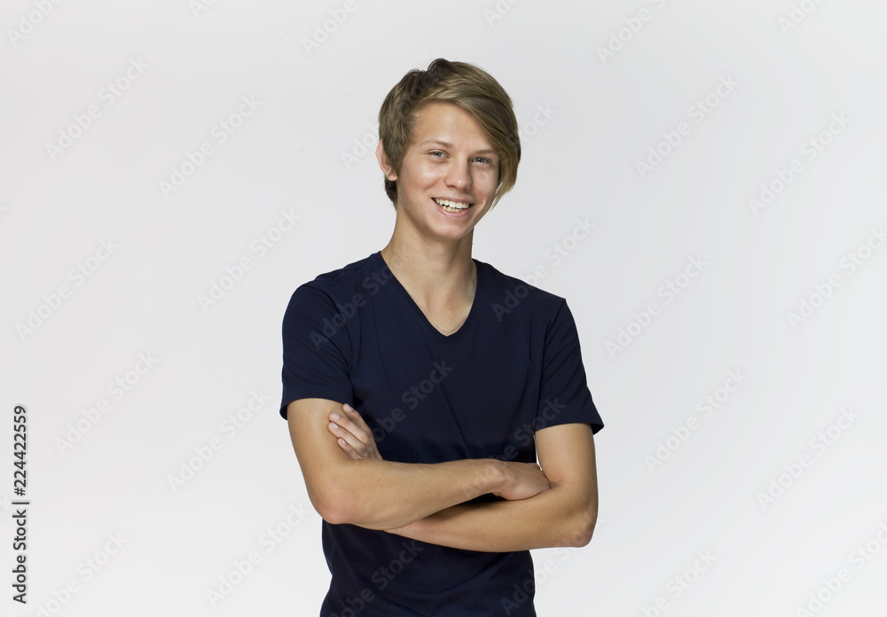 Cheerful smiling teenager in blue, black t-shirt with crossed arms against white background studio shot, isolated Cheerful smiling teenager in blue, black t-shirt with crossed arms against white background studio shot, isolated