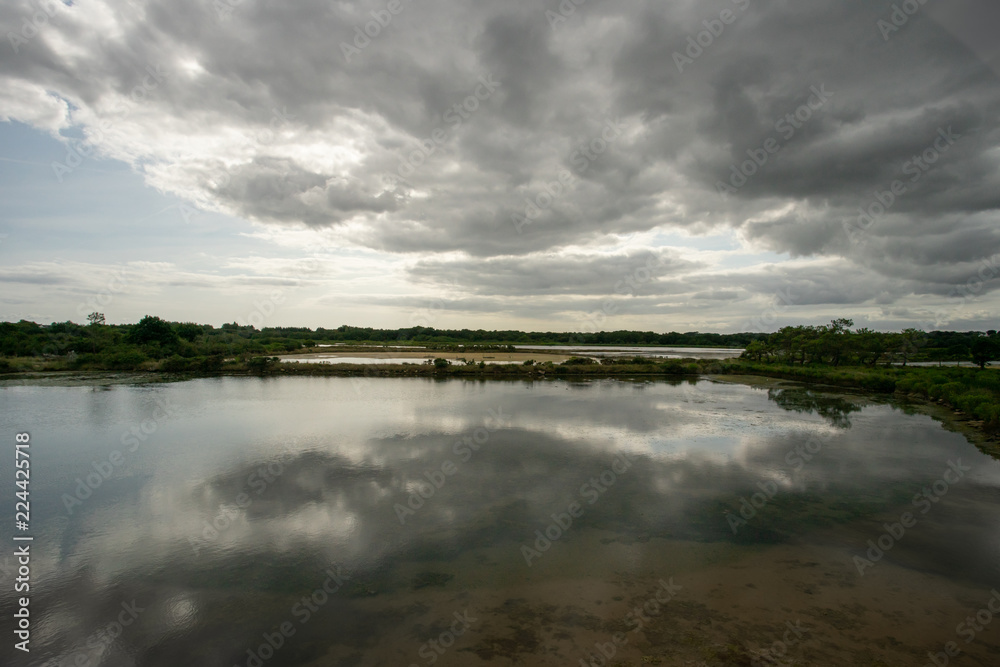 un étang avec un ciel nuageux, menaçant et son reflet