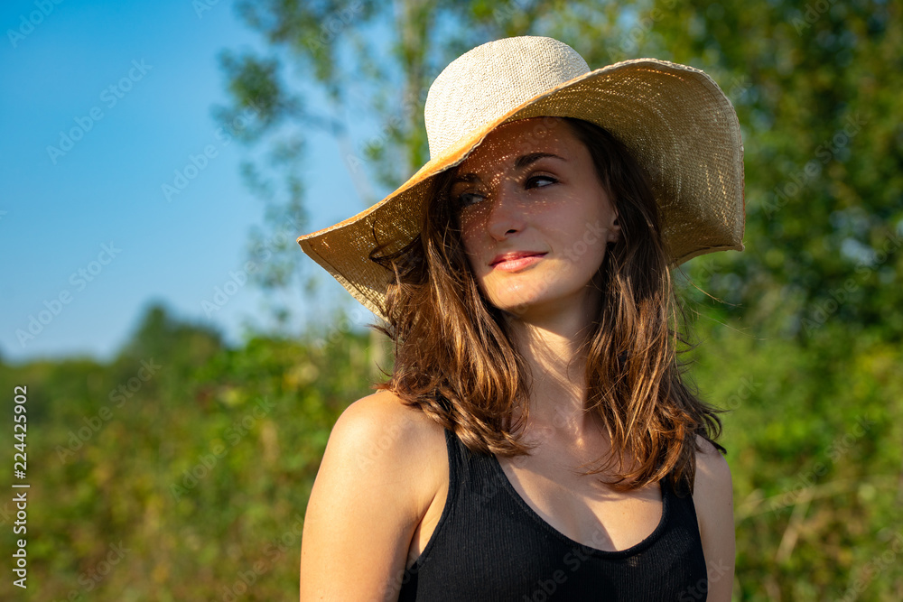 portrait d'une femme brune au cheveux long en robe noire et un grand chapeau  de paille élégant Stock Photo | Adobe Stock