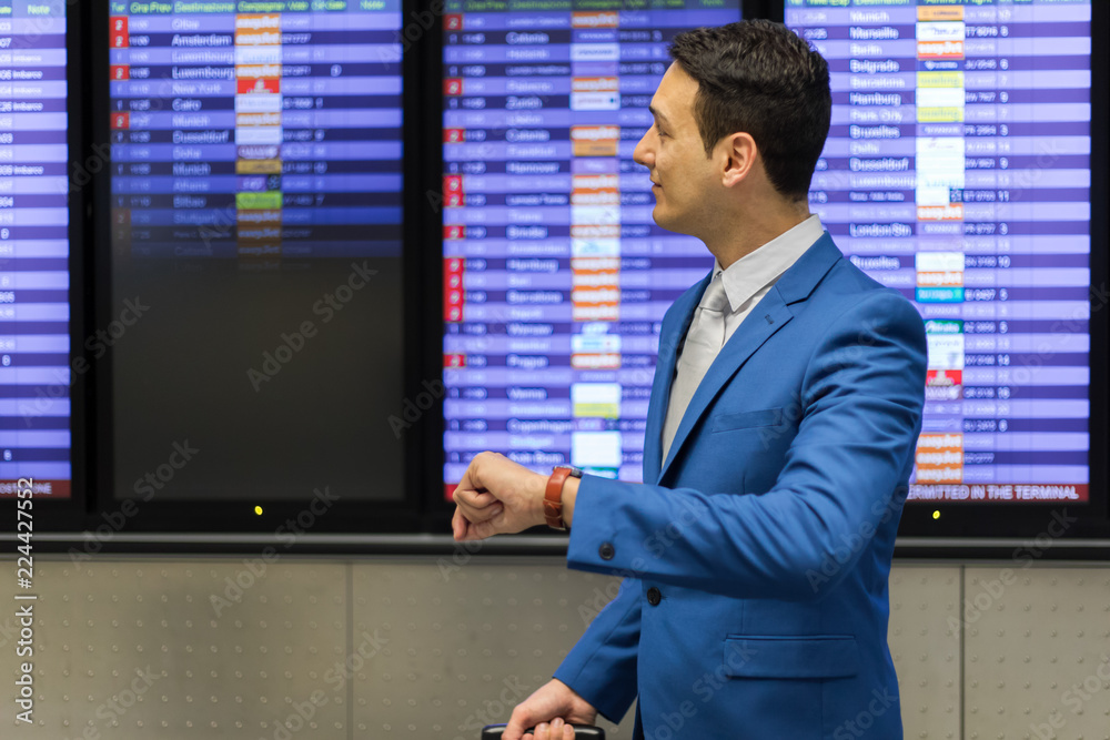 Businessman checking time in the airport, flight delay concept Businessman checking time in the airport, flight delay concept
